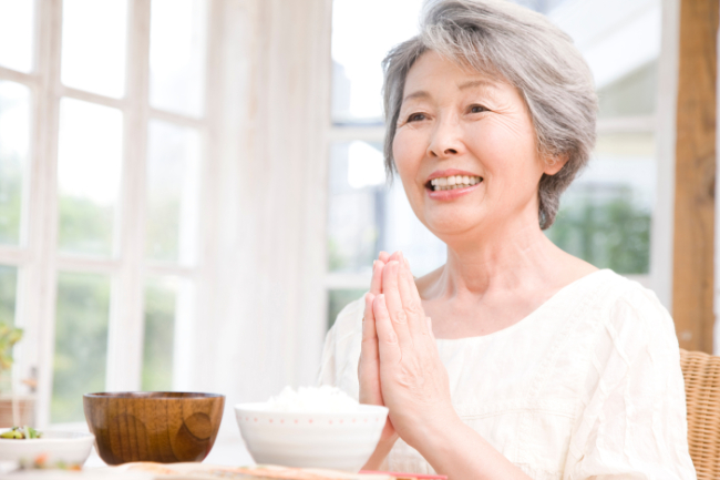 入れ歯治療を終え美味しく食事をとる女性