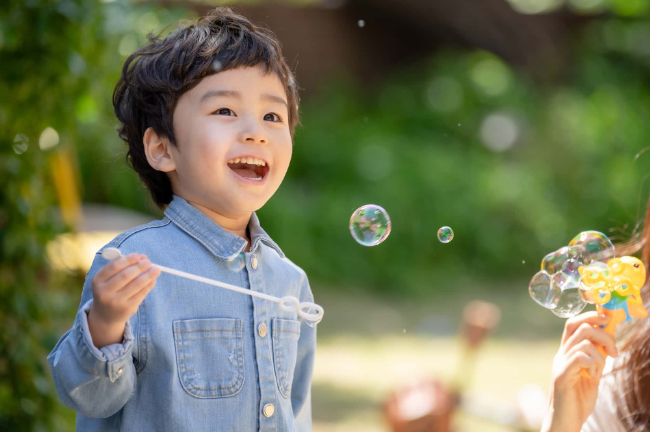 フッ素塗布で虫歯のない男の子がシャボン玉を作って遊んでいるイメージ