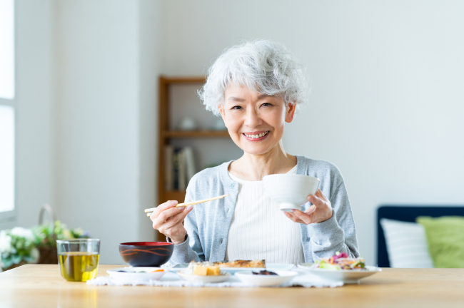 自分に合った入れ歯を装着し美味しく食事をする女性