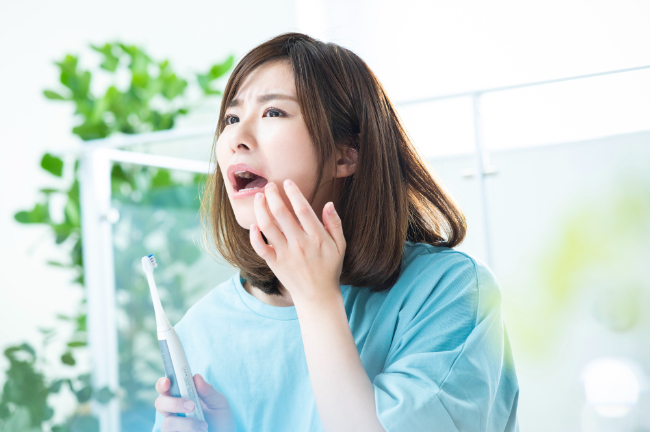 インプラント治療後に歯磨きを怠り違和感を感じる女性