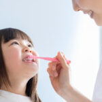 母親に歯磨きをしてもらう女の子